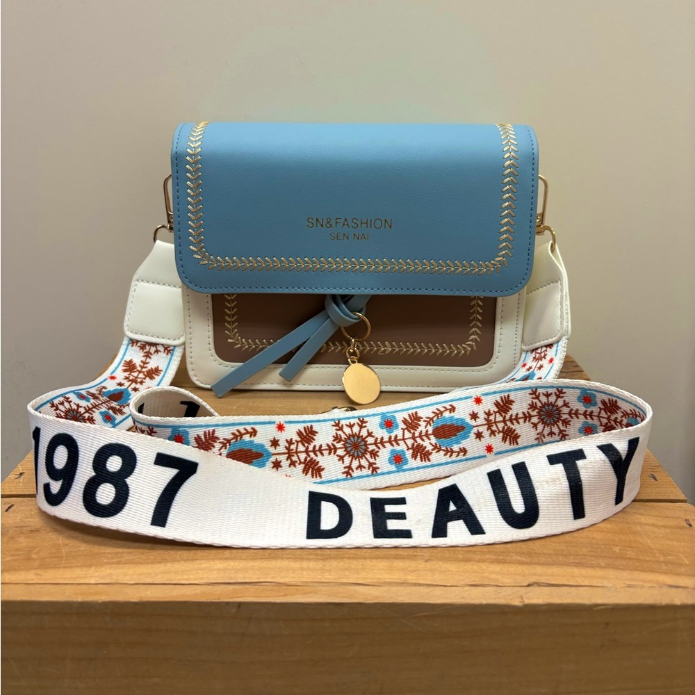 Chic pastel bag with gold accents and a bold embroidered strap!!